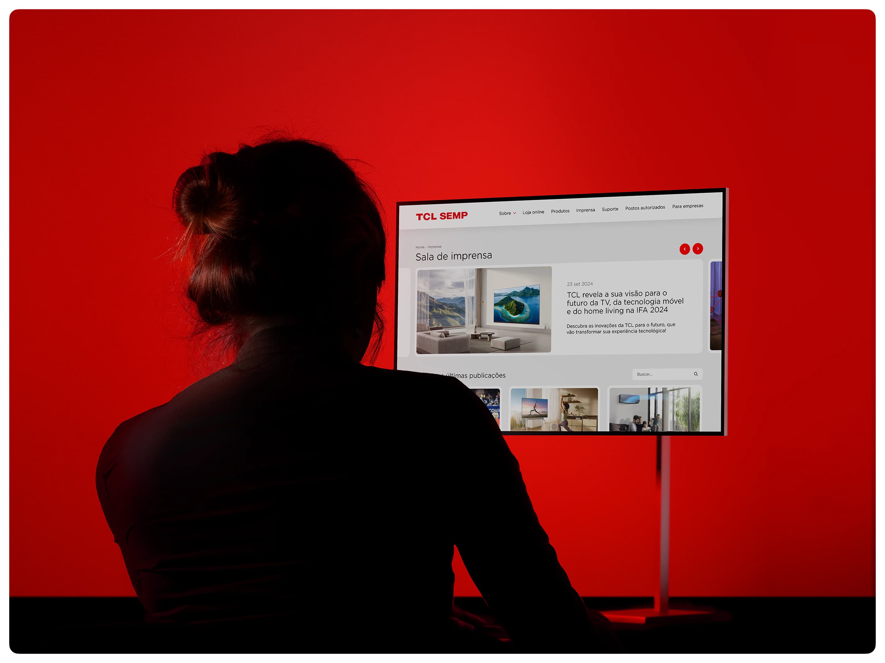 Pessoa diante de um monitor com o site da TCL SEMP, sobre fundo vermelho